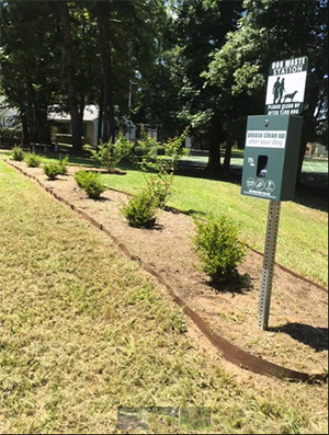 Dog pooper scooper stand along a mulched walkway